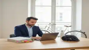 Directeur des ressources humaines en train d'analyser les obligations de la loi LOM pour son entreprise, avec casque de vélo sur le bureau et vélo visible dehors
