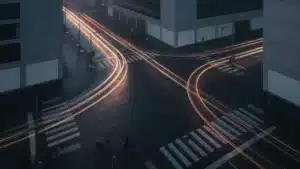 Carrefour urbain au petit matin, traînées lumineuses des véhicules en pose longue et cyclistes arrêtés au passage piéton