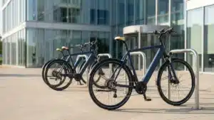 Trois velos electriques bleu marine gares cote a cote devant un immeuble de bureaux vitre